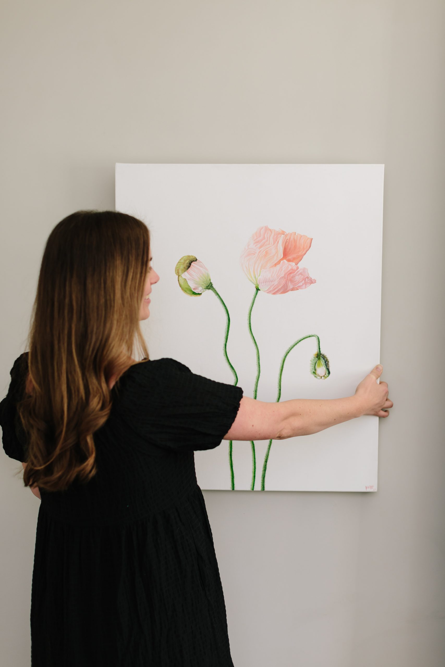 Kenan Hill hanging an original acrylic painting of pink poppies from 3 Porch Farm