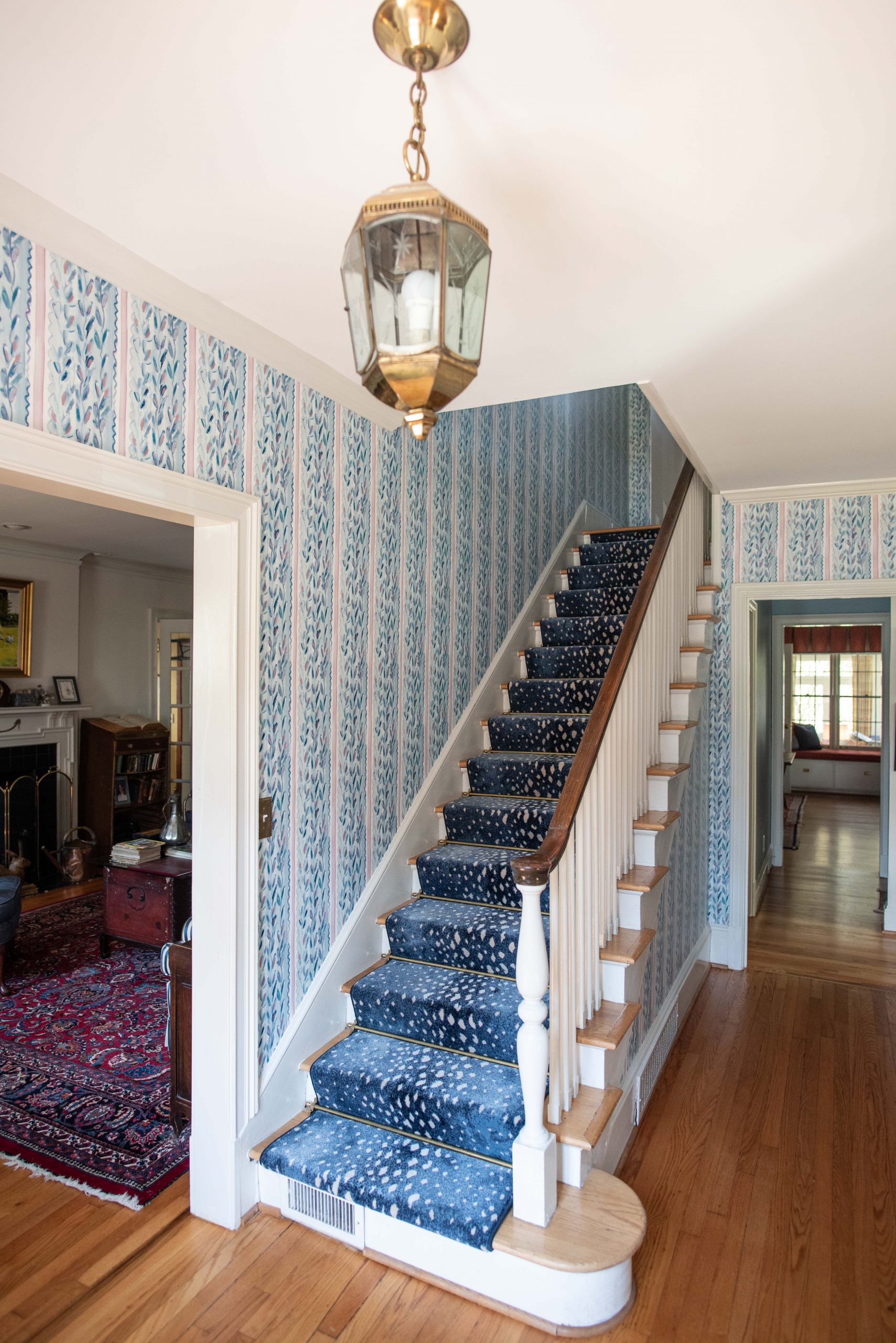 Traditional foyer with blue striped wallpaper and a blue stair runner
